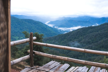 Fototapeta premium Landscape image of greenery rainforest and hills on foggy day from wooden balcony