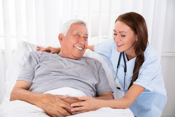 Nurse Looking At Happy Male Patient In Clinic