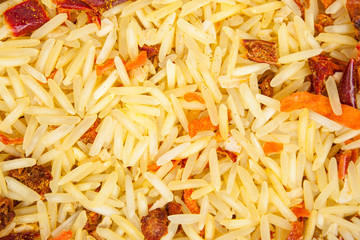 Background texture of basmati rice with dried carrots, onions, paprika, tomato, garlic and ground spices (turmeric, coriander and chili pepper). Top view. Close-up.