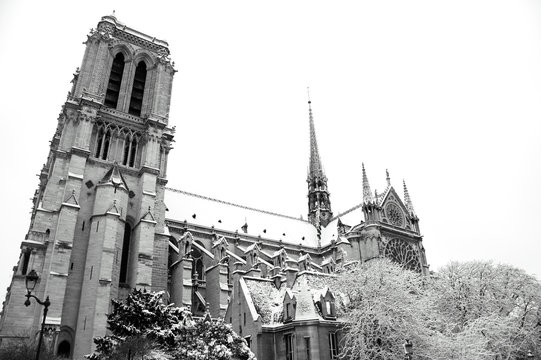 Notre Dame cathedral (Paris, France) covered with snow in rare snowy winter day. View from the bridge. Black and white photo.