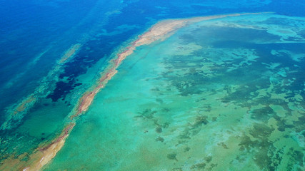 Aerial drone bird's eye view photo of tropical and exotic coral reef forming an atoll archipelago with beautiful sapphire and turquoise open ocean - obrazy, fototapety, plakaty