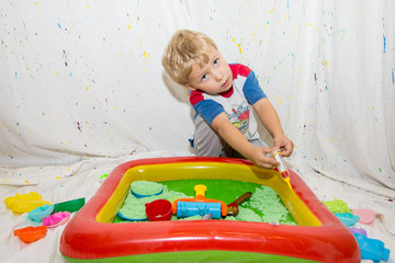 children play in an inflatable pool with kinetic sand