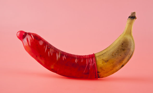 banana and red condom on a pink background