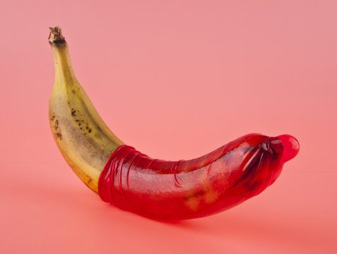 banana and red condom on a pink background
