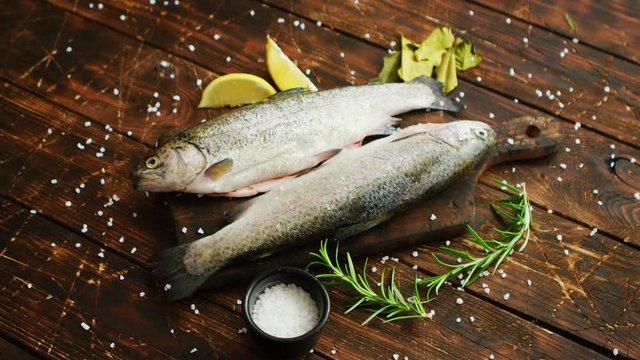 From above shot of aromatic slices and slices of fresh lemon lying on lumber tabletop around uncooked trout