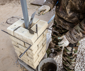 The worker is laying bricks on the fence