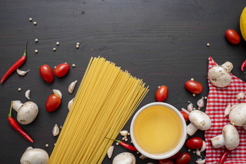 Spaghetti ingredients on black wooden desk, top view.