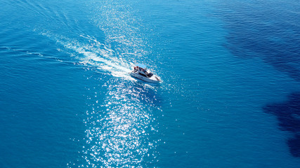 Aerial bird's eye view photo taken by drone of boat cruising in caribbean tropical beach with turquoise - sapphire waters