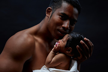 brutal handsome dad is hugging his baby, isolated on the black background.