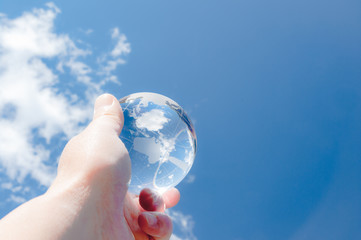 青空を背景にガラスの地球を掲げる手