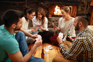 Young people playing cards on winter holiday - obrazy, fototapety, plakaty
