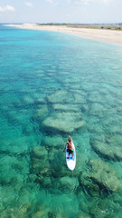 Aerial drone photo of couple practicing Stand Up Paddle or SUP in tropical exotic emerald and...