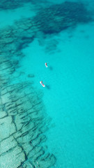 Aerial drone photo of couple practicing Stand Up Paddle or SUP in tropical exotic emerald and sapphire island sea