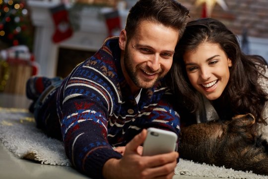 Christmas couple with phone at home in Winter