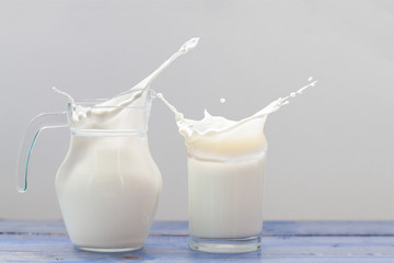 Splash of milk from the milk glass ,Morning milk, Glass jug and glass with milk on a wooden table on white background