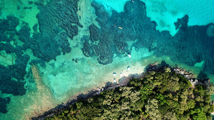 Aerial photo of iconic white cliff tropical bay forming a blue lagoon with deep turquoise clear ocean and docked small boats enjoying this unique paradise