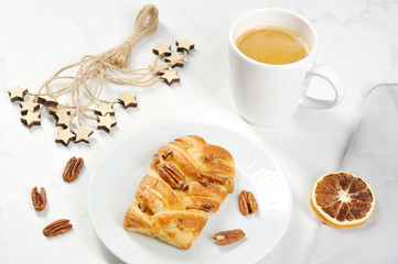 Maple pecan on a plate. Near a cup of coffee. The composition is supplemented with a slice of dry orange, pecans and a napkin made of cloth. Light background. Close-up.