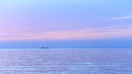 Fototapeta na wymiar cargo boat sailing near the shore / sunrise on a wild beach Ukraine