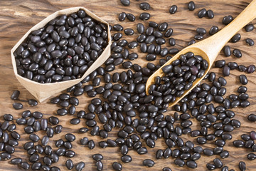Raw black beans on the wooden background
