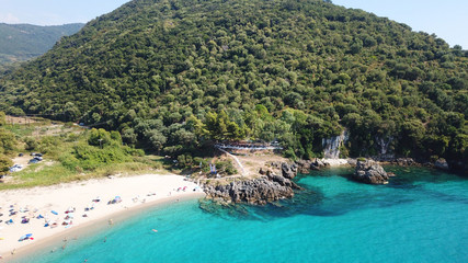 Obraz premium Aerial drone bird's eye view of popular beach of Karavostasi with beautiful clouds and turquoise sandy beach full of sunbeds at summertime, Epirus, Ionian, Greece
