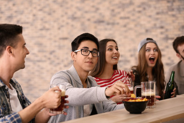 Group of cheerful friends drinking beer in bar