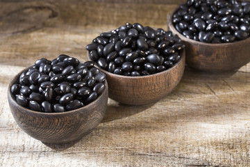Raw black beans on the wooden background