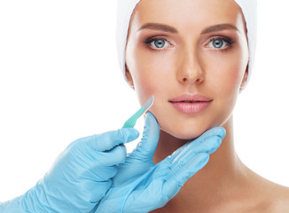 Beautiful face of the young woman and the medical scalpel in doctor's hands isolated on white. Plastic surgery and face lifting concept. - obrazy, fototapety, plakaty