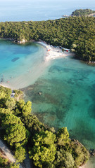 Aerial drone bird's eye view photo of popular and iconic turquoise beach of Bella Vraka in island of Mourtemeno with sunbeds and canoes forming a blue lagoon, Sivota bay, Epirus, Greece