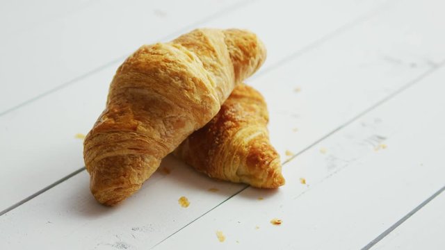 Closeup shot of two delicious fresh croissants lying on one another on surface of white wooden table