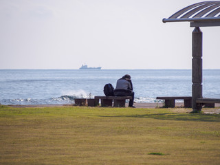 海岸のベンチに座る男性