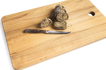 small bar of wholemeal bread with freshly made walnuts next to a knife on a wooden board
