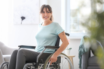 Happy young woman in wheelchair at home - obrazy, fototapety, plakaty