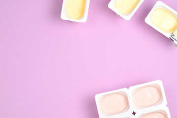 Plastic cup with tasty yogurt on lilac background. Top view. Space for text or design.
