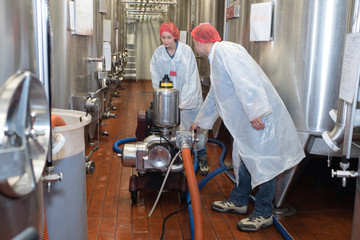 woman and man in uniform work with equipment to winery