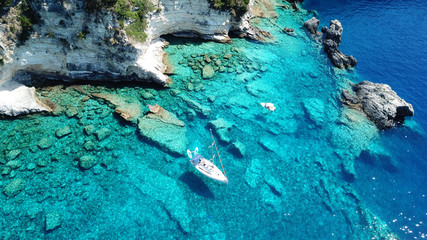 Obraz premium Aerial drone bird's eye view photo of sail boats docked in tropical caribbean paradise bay with white rock caves and turquoise clear sea