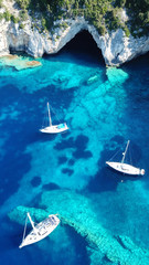Obraz premium Zdjęcie lotnicze drona z lotu ptaka kultowej tropikalnej, skalistej rajskiej zatoki zwanej błękitną laguną z jaskiniami i turkusowo czystymi wodami odwiedzanymi przez żaglówki, wyspa Paxos, Joń, Grecja