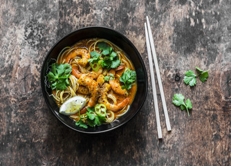 Shrimp laksa soup on a dark wooden background, top view. Copy space. Asian style food
