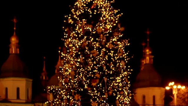 Glowing lights turning into a holistic picture of christmas tree. Eastern European city in the background.