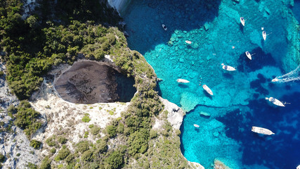 Aerial drone bird's eye view photo of iconic tropical rocky paradise bay called blue lagoon with caves and turquoise clear waters visited by sail boats, island of Paxos, Ionian, Greece