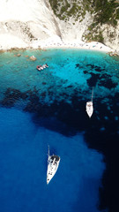 Aerial drone bird's eye view photo of sail boats docked in tropical caribbean paradise bay with white rock caves and turquoise clear sea