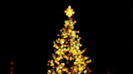 Yellow blurred lights on the christmas tree. Camera is moving up from the bottom.