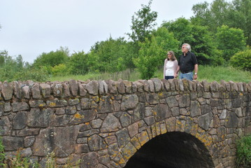 man and woman walking over stone bridge
