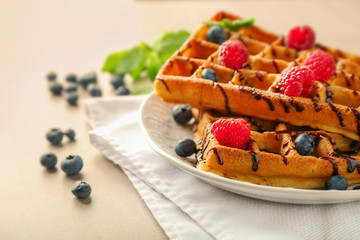 Delicious waffles with berries and chocolate sauce on plate
