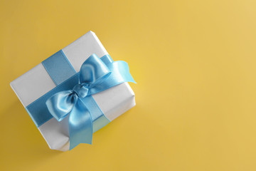 Gift box with blue ribbon on color background