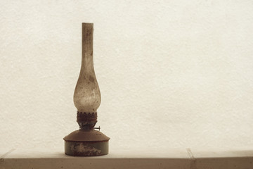 An old vintage kerosene lamp on the background of a white wall. Copy space.