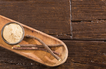 Licorice powder and roots - Glycyrrhiza glabra. Wooden background