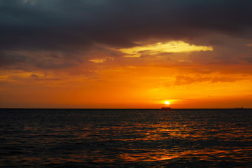 sunset and ship on horizontal ocean water surface colorful cloud sky