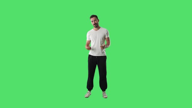 Happy young relaxed casual man talking and explaining while gesticulating hands looking at camera. Full body isolated on green screen background. 