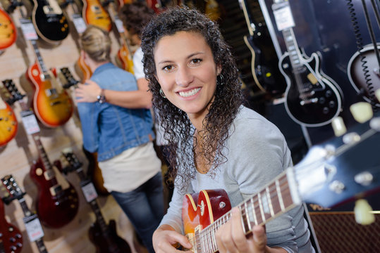 adult female customer trying to play new guitar in store