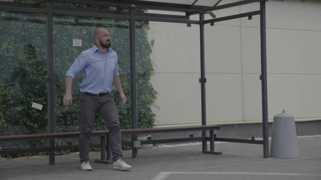 Handsome businessman starting dancing freestyle funny dance while he is happy waiting for bus in a public station